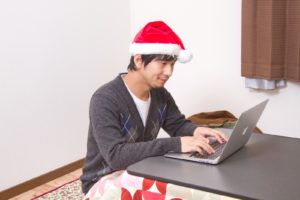 サンタの帽子を被ってパソコンを叩く男性